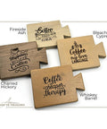 Four wooden coasters with coffee-themed engravings. Designs include "Happiness is a cup of coffee," "Coffee is my love language," "Coffee is cheaper than therapy," and "Coffee is the best idea." Coasters are made from various wood types.