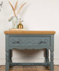 Wooden side table with decorative elements on a wooden floor, branded 'Upcycled by Nicci'.