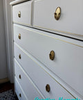 White dresser with gold handles in a room setting