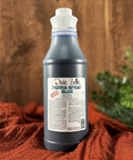 A 32 oz. bottle of Dixie Belle Blue Patina Spray. Displayed on a wooden background with an orange cloth.