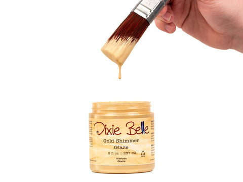 Jar of Dixie Belle Gold Shimmer Glaze with a brush dipping into it on a white background