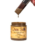 Jar of Dixie Belle Van Dyke Brown Glaze with a brush dipping into it on a white background