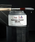Dixie Belle Patina Paint Iron with a brush on a dark background
