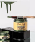 Jars of 'Dixie Belle Moonshine Metallics' with a paintbrush on a glass surface.