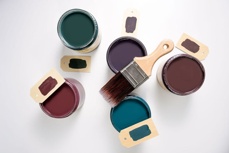 Five open paint cans with lids and a paintbrush on a white background