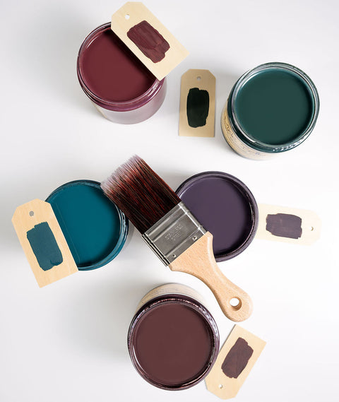 Five open paint cans with lids and a paintbrush on a white background