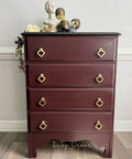 Wooden dresser with gold handles against a gray wall
