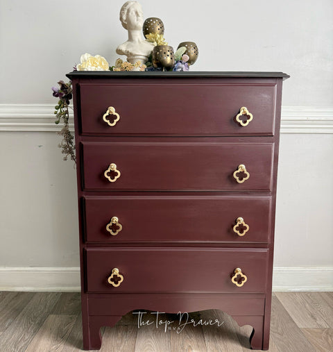 Wooden dresser with gold handles against a gray wall
