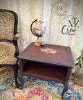 Decorative side table with a leopard print chair and floral rug in a room setting.