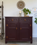 Dark wooden cabinet with decorative elements in a room with plants and a ladder.