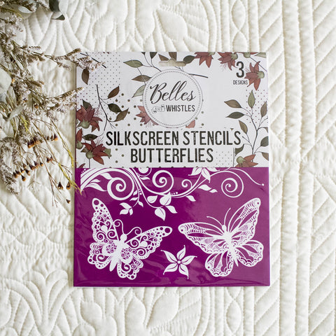 Silkscreen stencils with butterflies on a textured white surface with floral elements.
