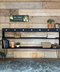plant stand painted with black all in one paint staged with plants and vases in front there is a rug and a plant to the left