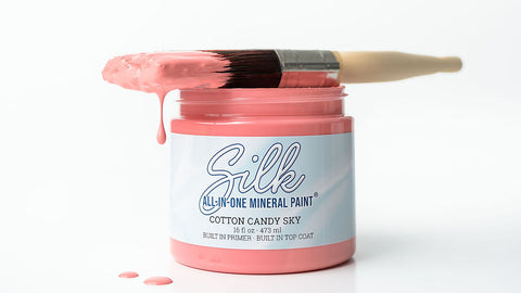 A jar of Silk cotton candy sky mineral paint with a paintbrush resting across the open jar, set against a clean white background.