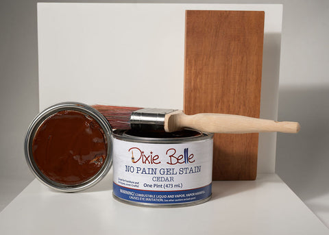 Can of Dixie Belle Cedar gel stain with a wooden stick on a white surface with a gray background