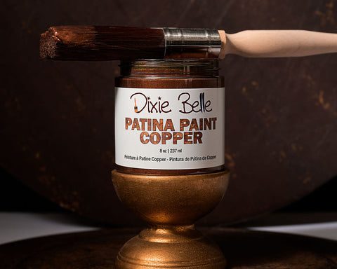 Jar of Dixie Belle Patina Paint Copper with a brush on a dark background