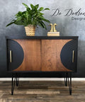 A side table chalk painted in black chalk paint with two sliding drawers.  with wood not painted, plant on top and a book with two duck heads for staging