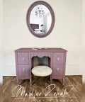 Purple vanity desk with round mirror and stool against a white wall, featuring 'Mad for Rehab by Aleshia' branding.
