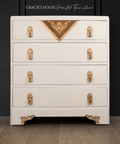 White dresser with gold accents and decorative elements on a dark background