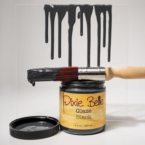 Dixie Belle Glaze Black can with a brush dripping black glaze on a white background