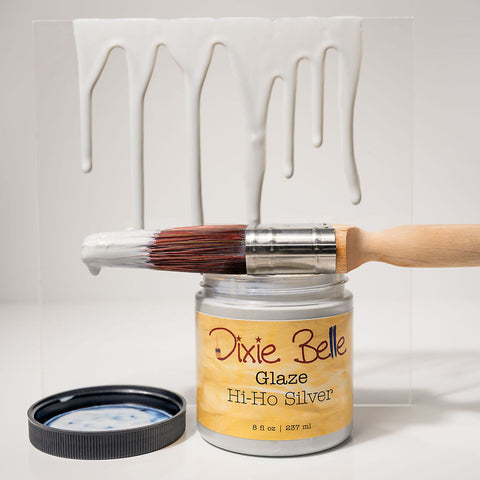 Jar of Dixie Belle Glaze Hi-Ho Silver with a brush and white painted object on a light gray background