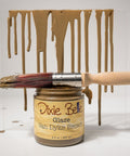 Jar of Dixie Belle Van Dyke Brown glaze with a brush and glaze dripping on a white background