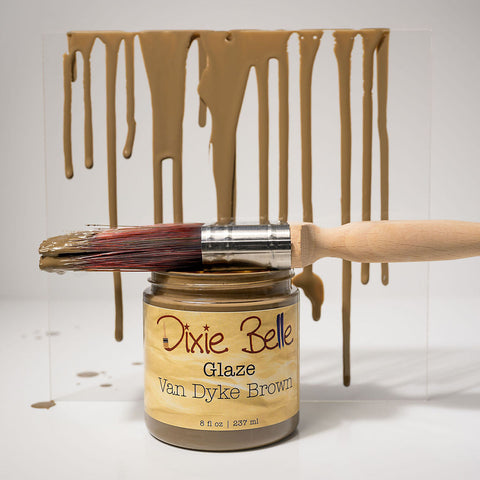 Jar of Dixie Belle Van Dyke Brown glaze with a brush and glaze dripping on a white background