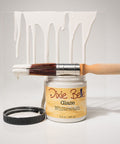 Dixie Belle Glaze Whitewash with a paintbrush and white paint on a gray background