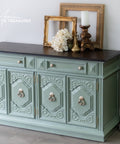 Decorative green sideboard with black top in a room setting.