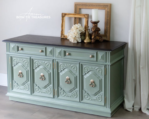 Decorative green sideboard with black top in a room setting.