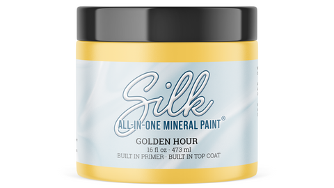 A jar of Silk All-In-One Mineral Paint in the shade Golden Hour, featuring a light yellow paint jar with a black lid and a light blue label.