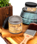 Dixie Belle glaze jars with a brush and wooden planter on a white background