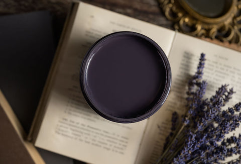 Black paint container on an open book with lavender flowers