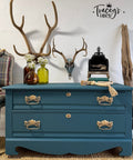 Blue dresser with gold handles in a room with decorative elements like antlers and vases.