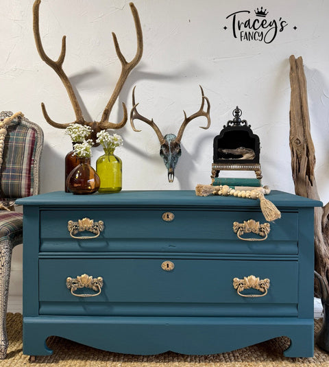 Blue dresser with gold handles in a room with decorative elements like antlers and vases.