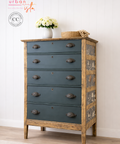 Wooden dresser with blue drawers and wooden frame against a white wall.