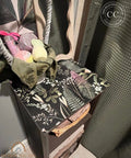 Decorative side table with floral pattern and items on top, featuring a visible brand logo.