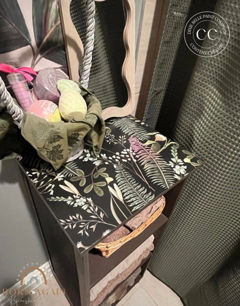Decorative side table with floral pattern and items on top, featuring a visible brand logo.