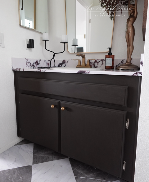 Bathroom vanity with dark brown cabinets, marble countertop, and decorative items.