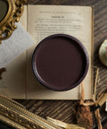 Container of brown paint on an open book with decorative elements