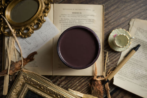 Container of brown paint on an open book with decorative elements