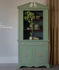 Green cabinet with decorative items against a plain wall
