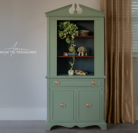 Green cabinet with decorative items against a plain wall