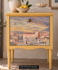 A yellow-painted wooden nightstand with a scenic Mediterranean cityscape decoupage on the front door, styled in a home interior setting. Label reads "Digital Rendering for Inspiration. Scale and sizing are approximate."