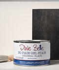 Dixie Belle Colonial Black gel stain can with a brush and sample swatch on a gray background