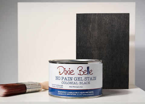 Dixie Belle Colonial Black gel stain can with a brush and sample swatch on a gray background