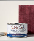 Can of Georgian Cherry Dixie Belle gel stain with a brush and swatch on a gray background