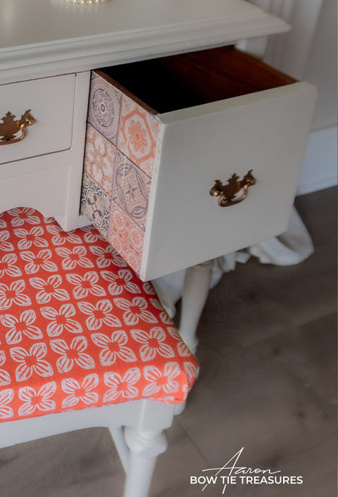 White dresser with a drawer open, revealing a colorful side, on a wooden floor.