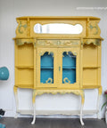 Yellow cabinet with decorative elements on a white background, featuring the brand 'Sisterhood Furniture'.