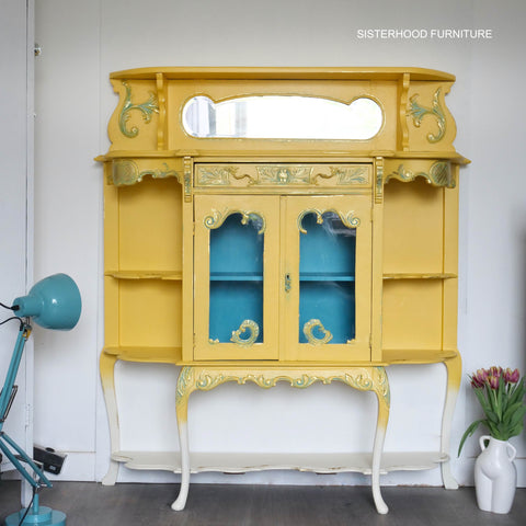Yellow cabinet with decorative elements on a white background, featuring the brand 'Sisterhood Furniture'.