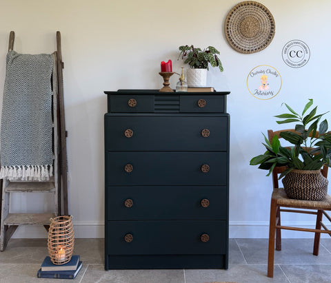 Dark green dresser with decorative items in a room with a ladder, plant, and lantern.